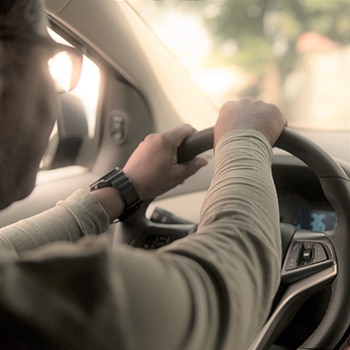 person driving car with hands on steering wheel